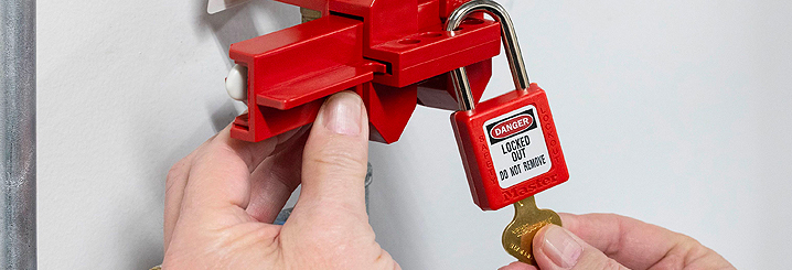 A close-up of two hands using a lockout padlock on a valve.