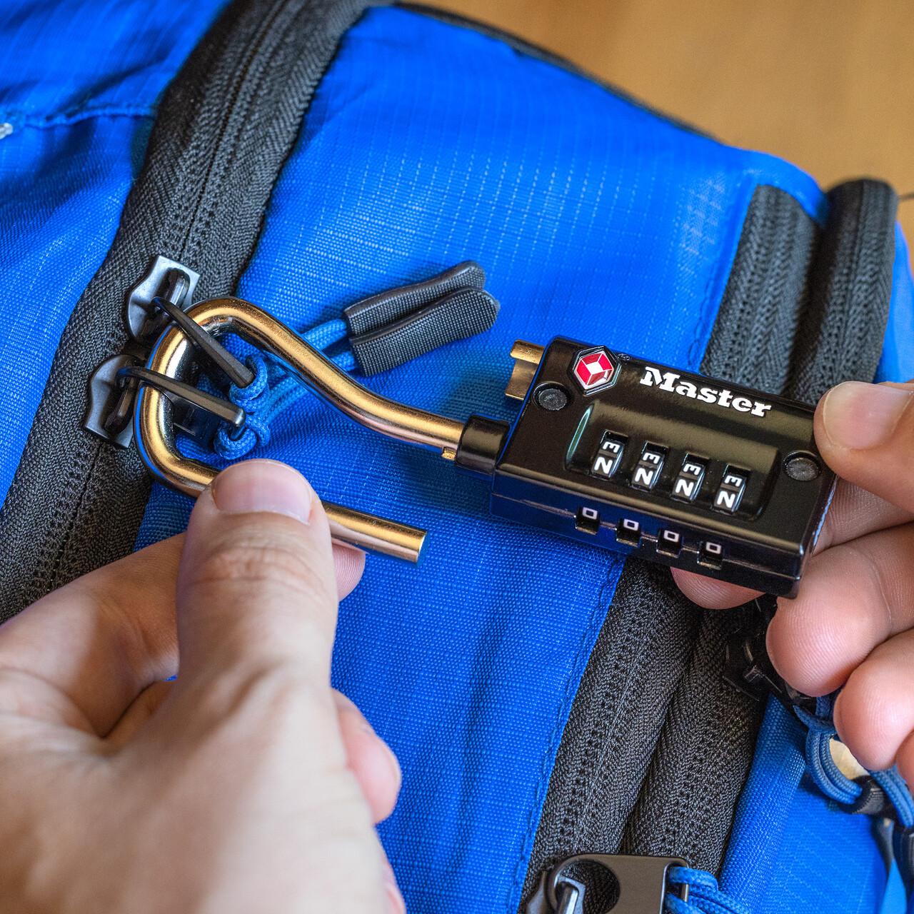 A luggage lock is placed on a blue piece of luggage
