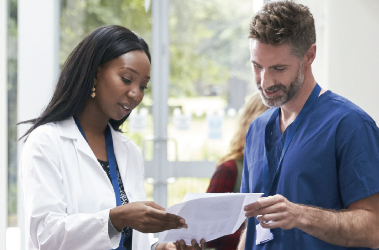 A female doctor and male nurse look over some paperwork
