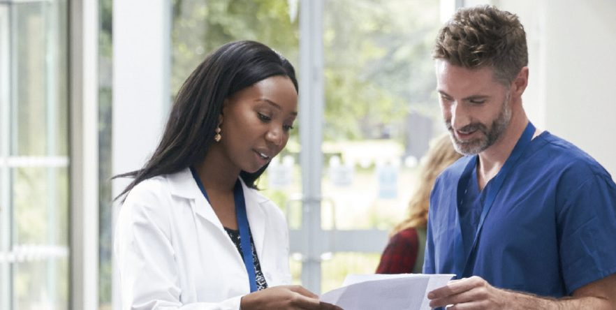 A female doctor and male nurse look over some paperwork